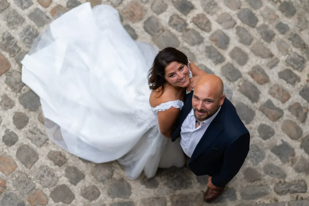 Couple de mariés souriant vu en plongée lors d’une séance photo de mariage sur pavés à Château -Thierry