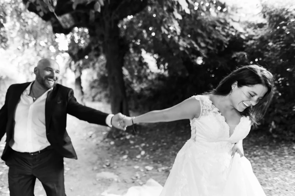 Mariés se tenant par la main et riant lors d’une séance photo de mariage en extérieur sur la promenade du vieux château de Château-Thierry