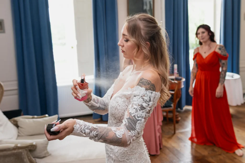 Mariée se parfumant avant la cérémonie dans un salon avec rideaux bleus, préparatifs de mariage au château de Vitry-la-Ville