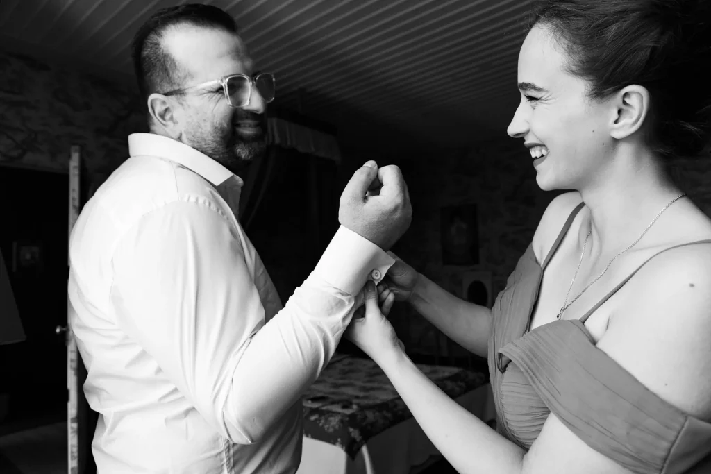 Marié souriant pendant qu’une proche ajuste sa manche avant la cérémonie