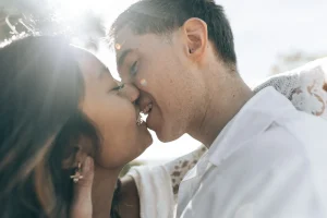 Les mariés s’embrassent en plein soleil pendant leur séance de couple